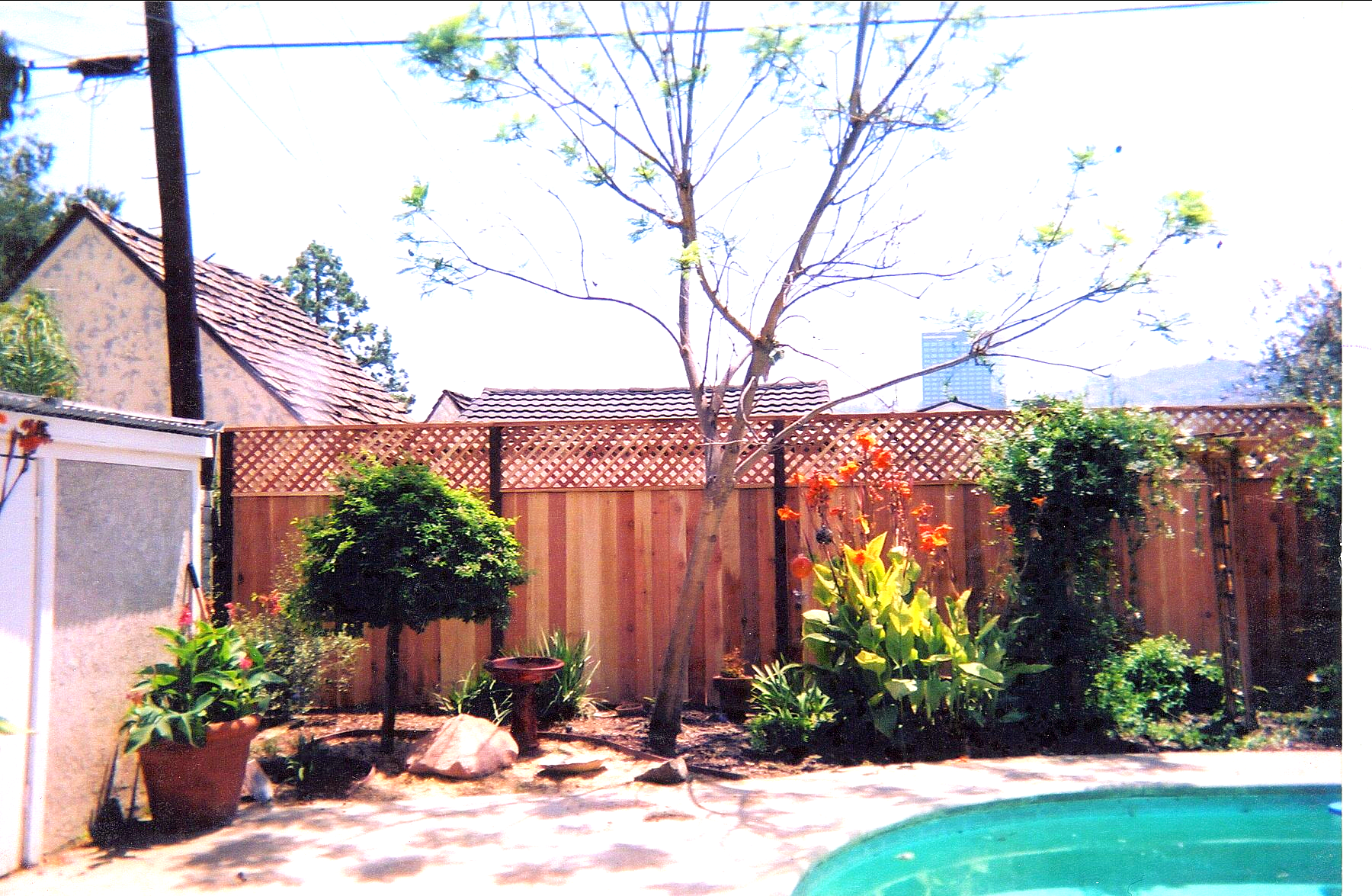 A backyard with a wooden fence and a swimming pool