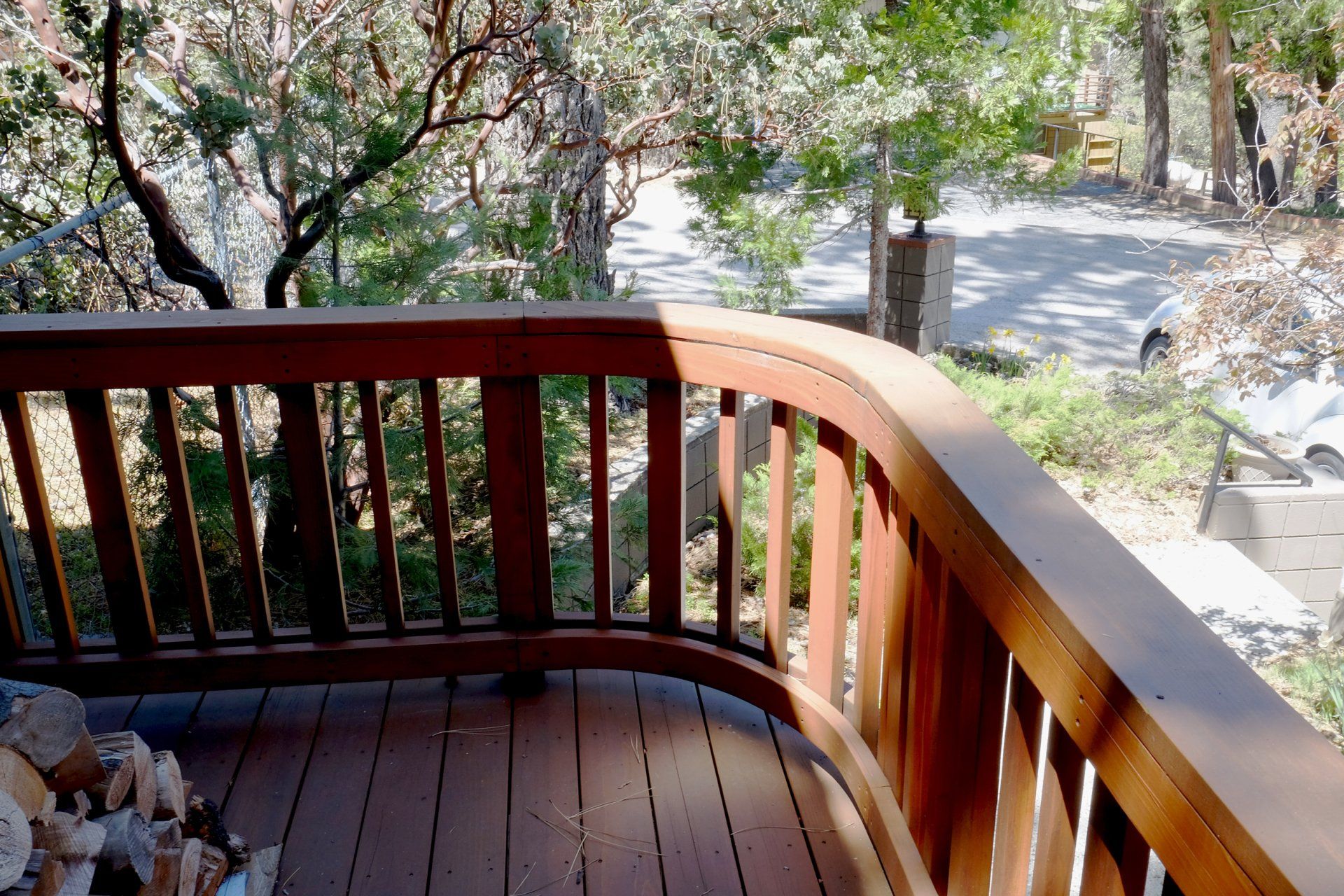 A wooden deck with a curved railing and trees in the background