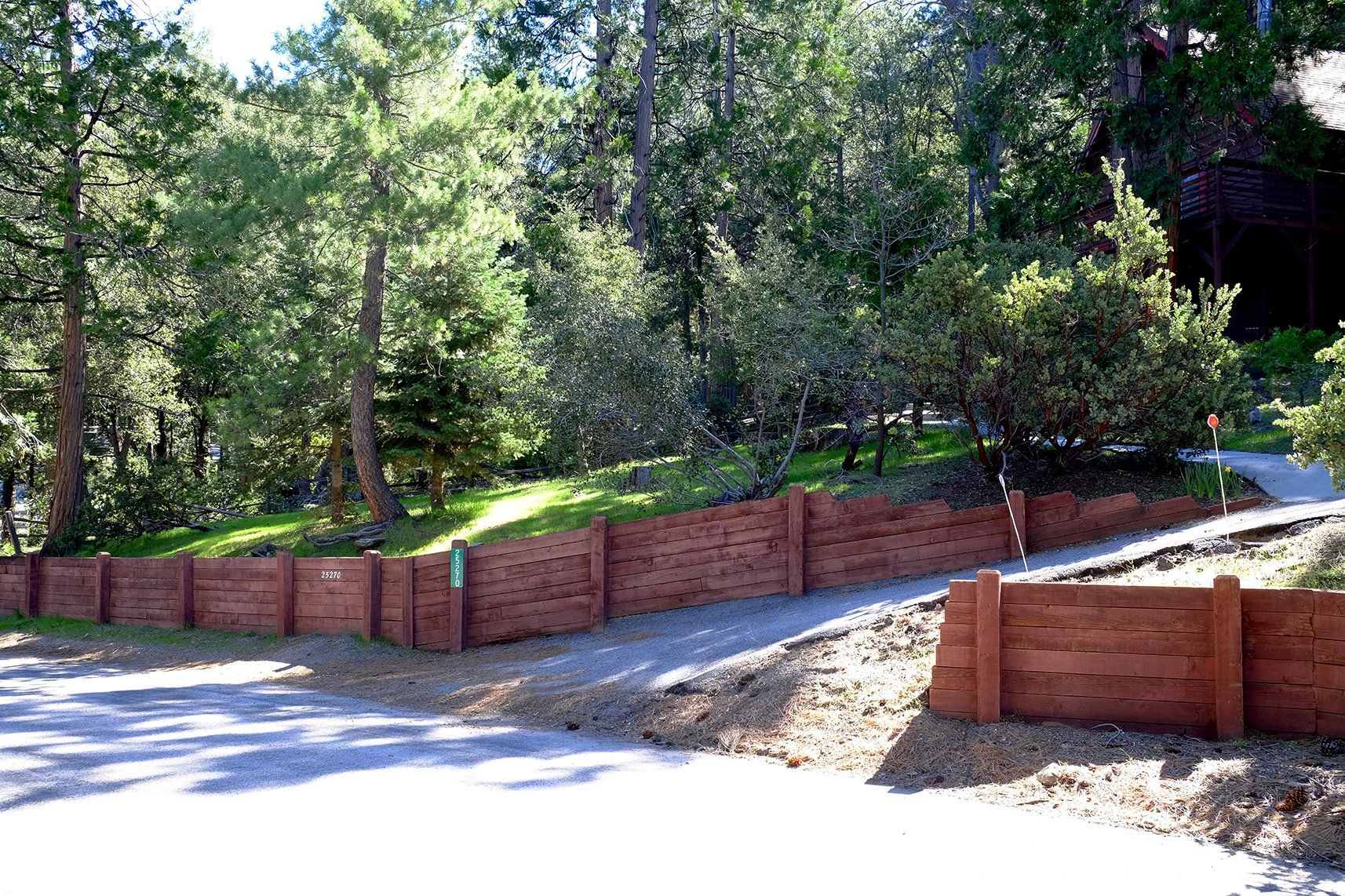 A wooden fence along the side of a road with trees in the background