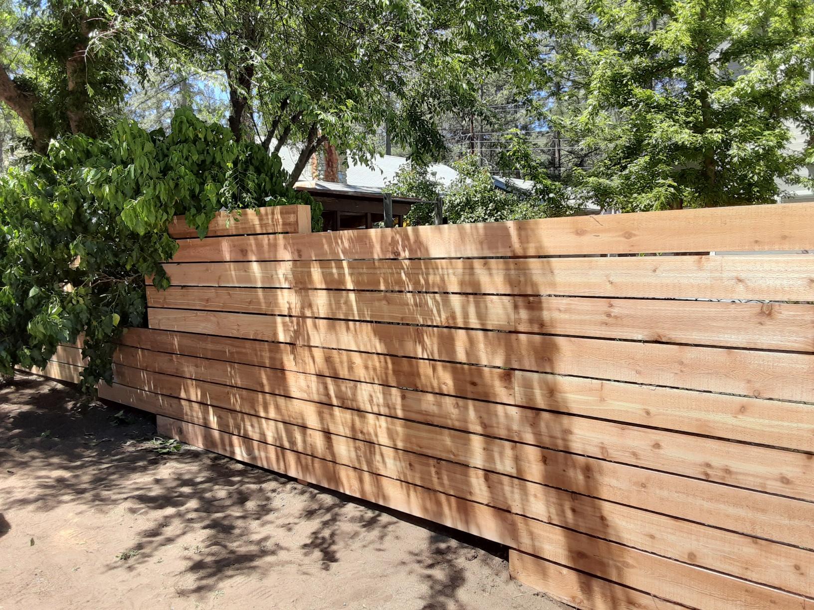 A wooden fence with trees in the background and a house in the background.