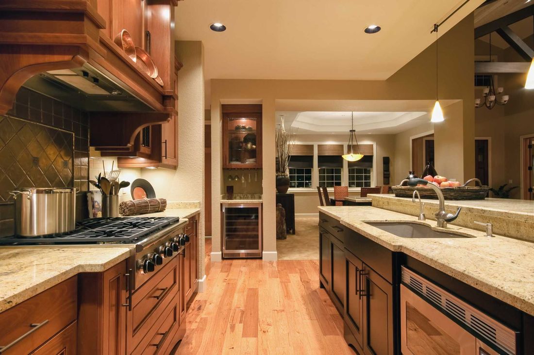 A kitchen with brown cabinets, light countertops, and wood floors. Dining area visible in the background.