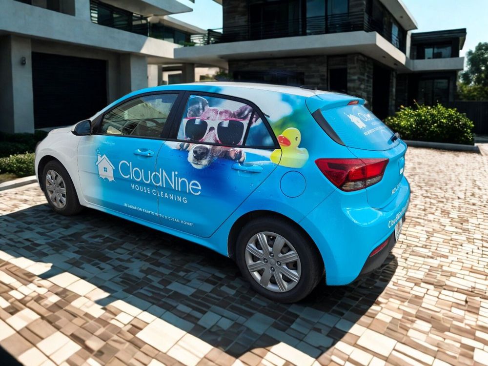 Blue CloudNine car with logo parked on a brick driveway in front of a modern house.