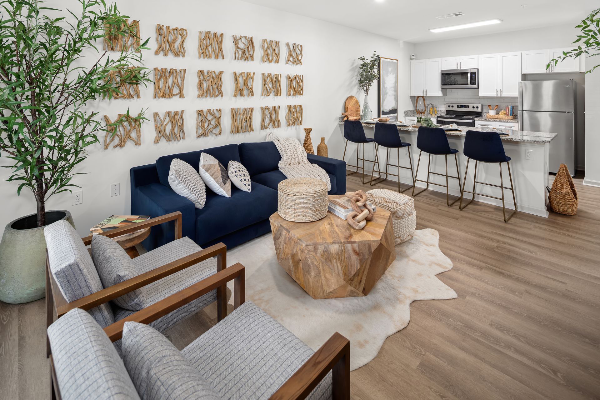 Modern living room with blue sofa, armchairs, and open kitchen.