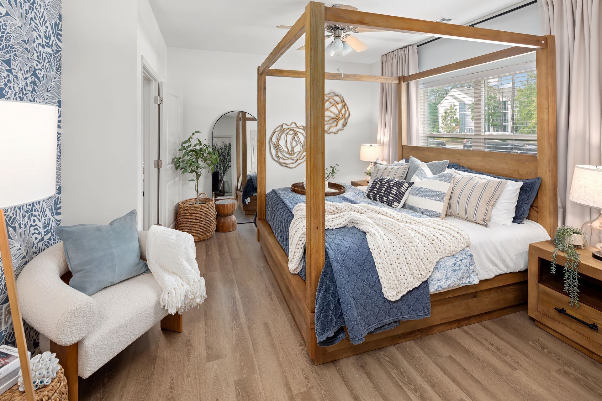 Bedroom with a large wooden canopy bed, blue and white bedding, and a seating area.
