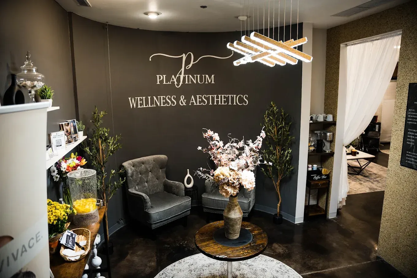 A waiting room with chairs , a table and a sign that says platinum wellness & aesthetics.