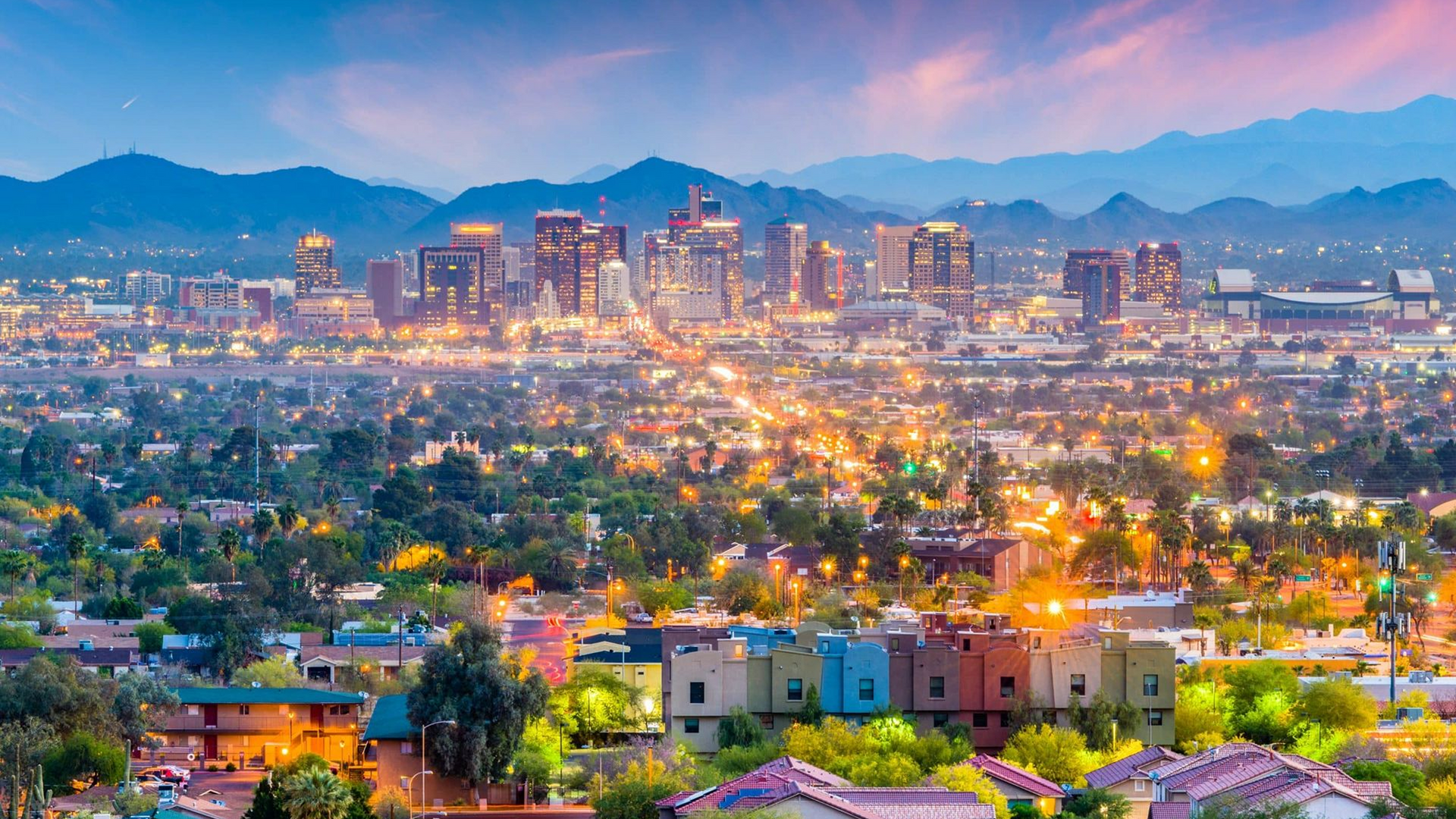 An aerial view of a city at night with mountains in the background.