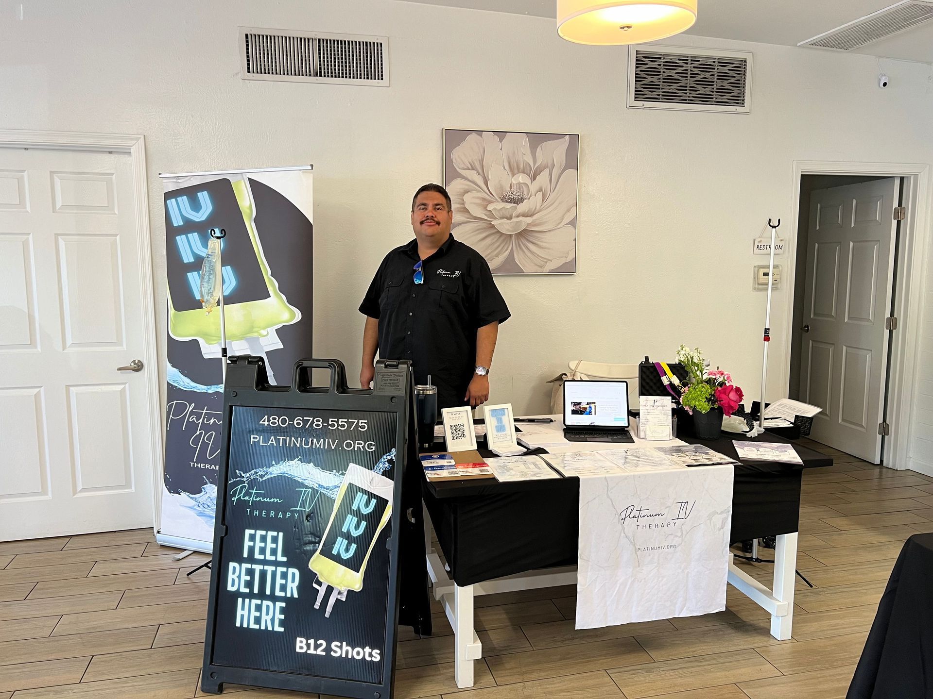 A man is standing in front of a table with a sign that says `` feel better here ''.