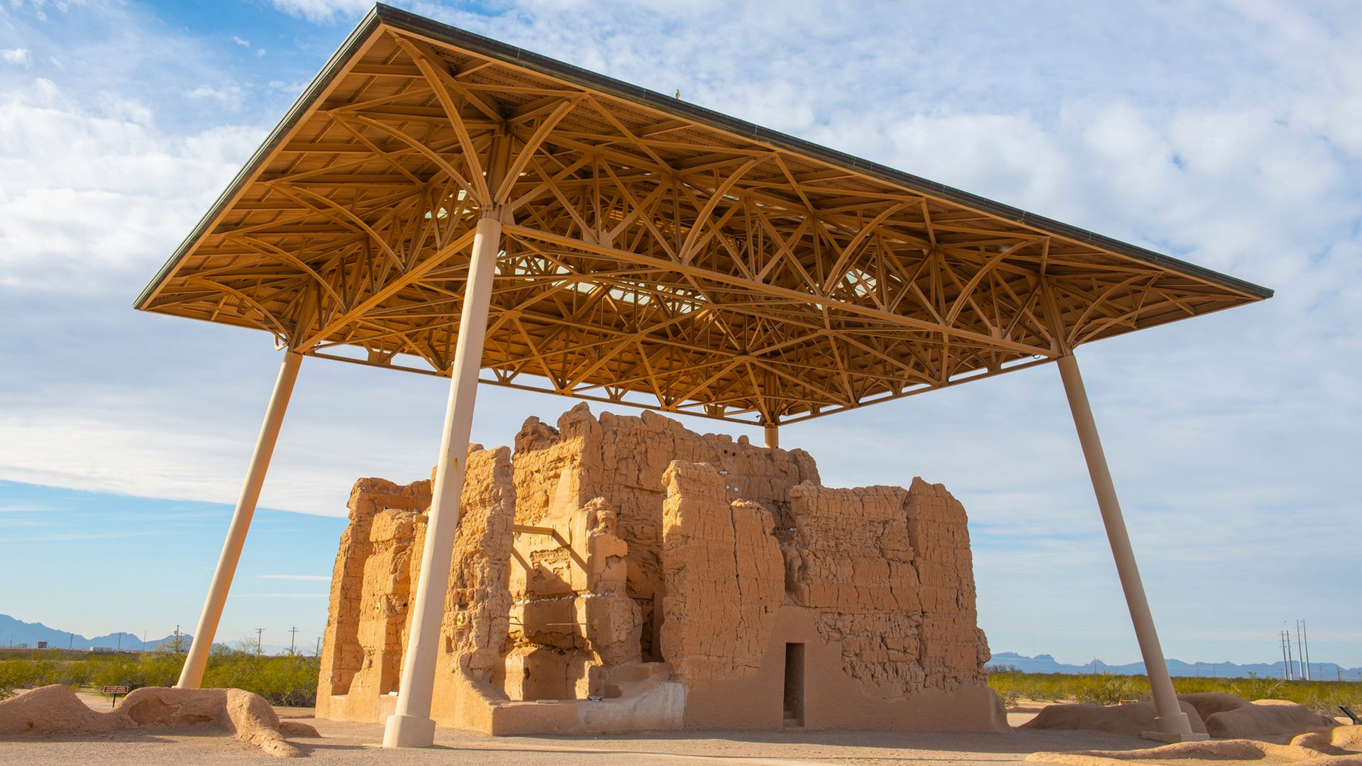 A large building with a wooden roof in the middle of a desert.