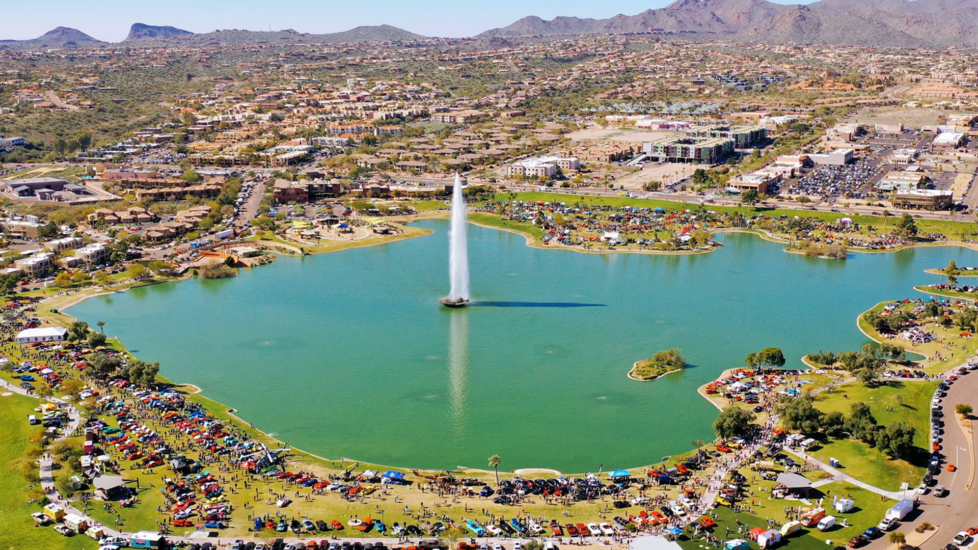 An aerial view of a large lake with a fountain in the middle of it.