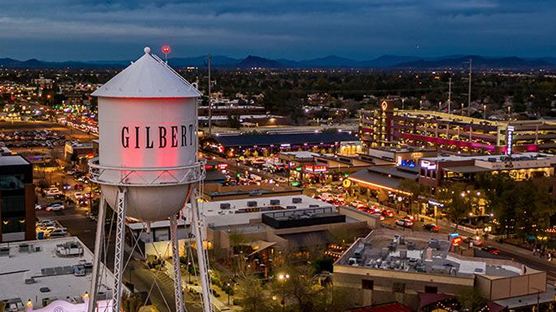 An aerial view of a water tower in a city at night.