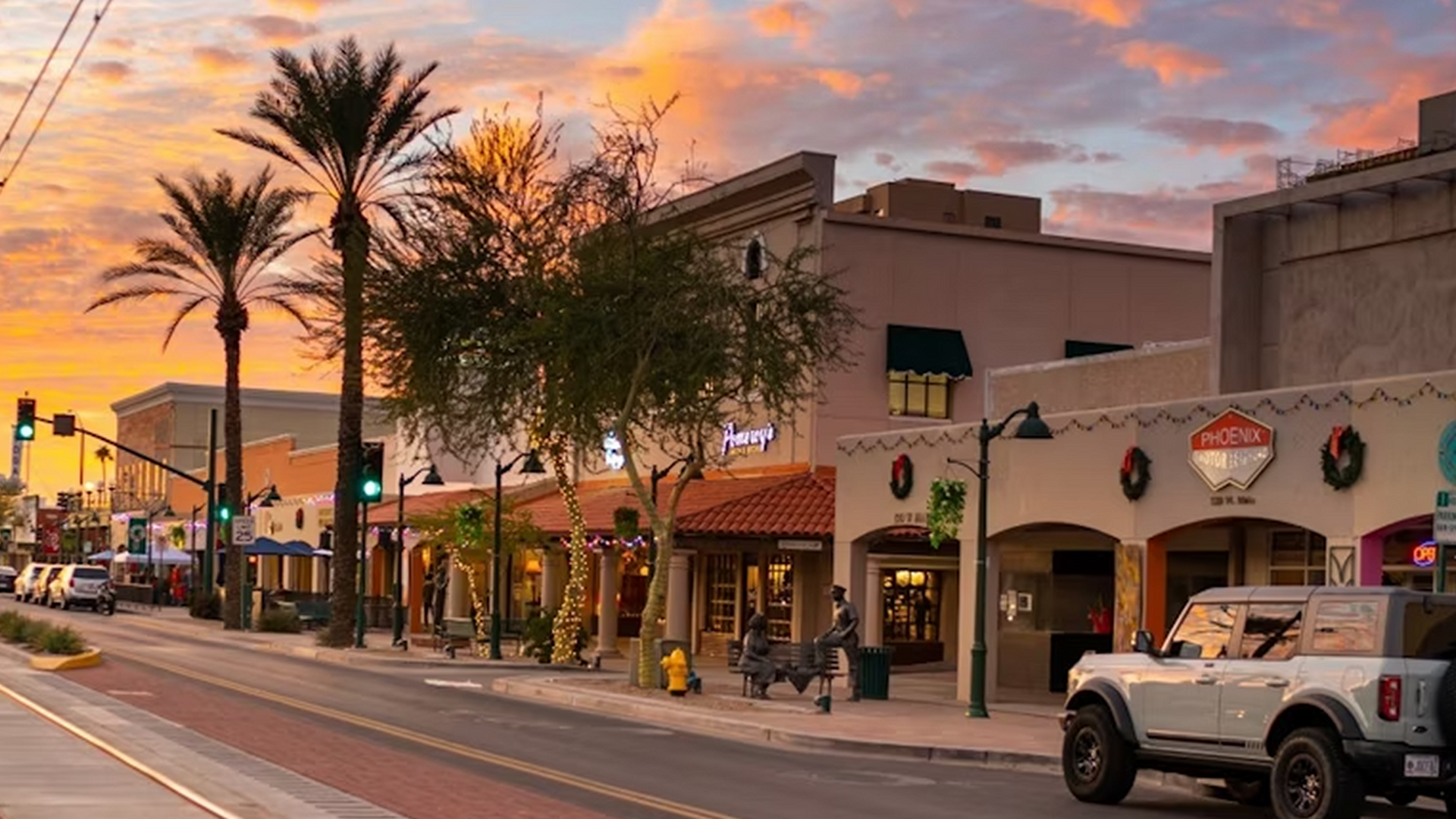 A white truck is parked on the side of a city street at sunset.