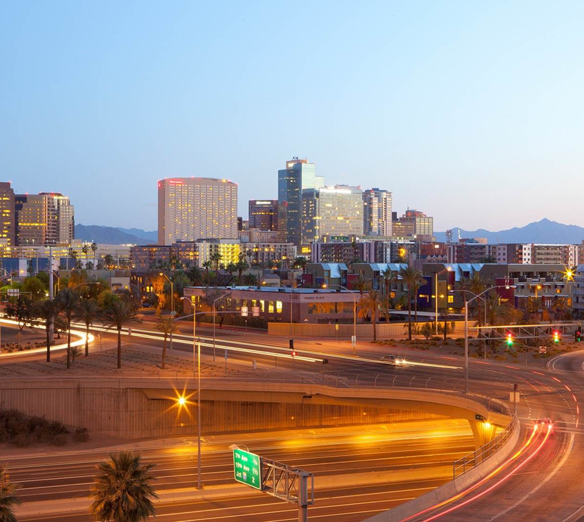 An aerial view of a city at night with a highway in the foreground.