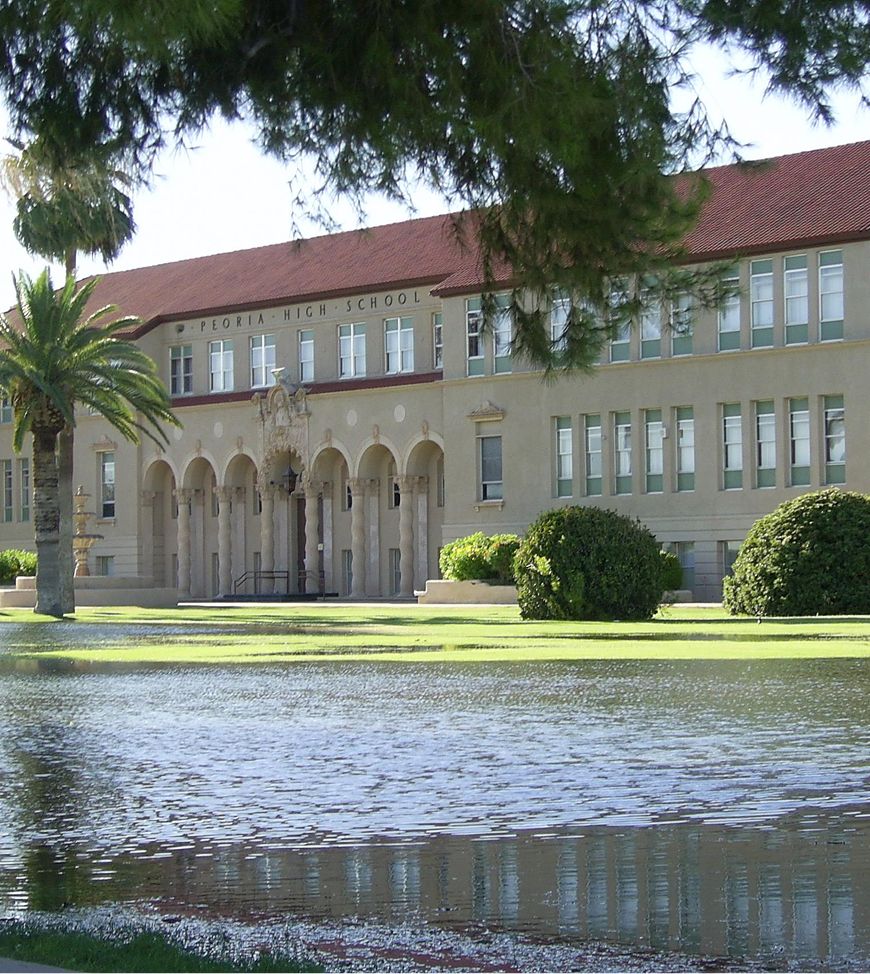 A large building with a red roof is surrounded by water