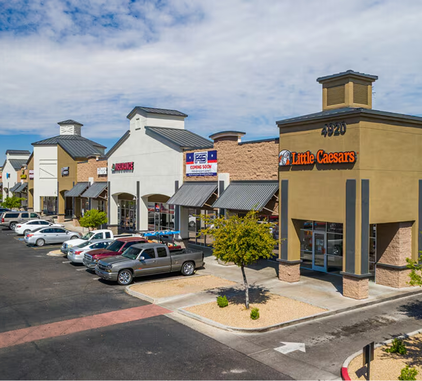 A lot of cars are parked in front of a little caesars restaurant