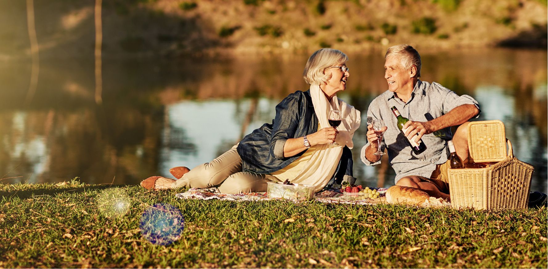 Happy older couple hugging, laughing outdoors in a green field on a sunny day. Magazine cover for connect.