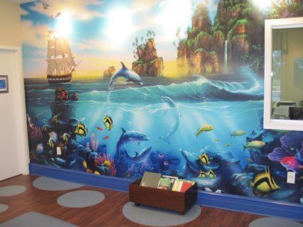 Mural of an underwater scene with dolphins, a ship, colorful fish, and a tropical island.