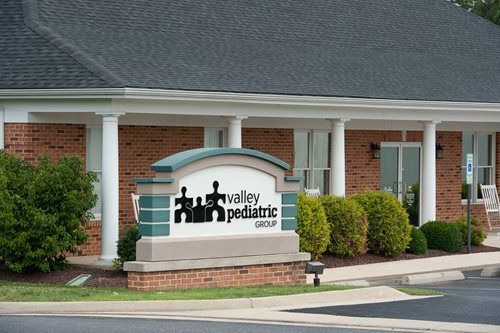 Valley Pediatric Group sign in front of a brick building with a dark roof and white pillars.