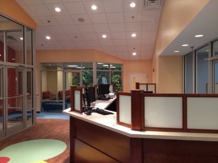 Reception desk with computer monitors and frosted glass panels, in a modern, well-lit office.