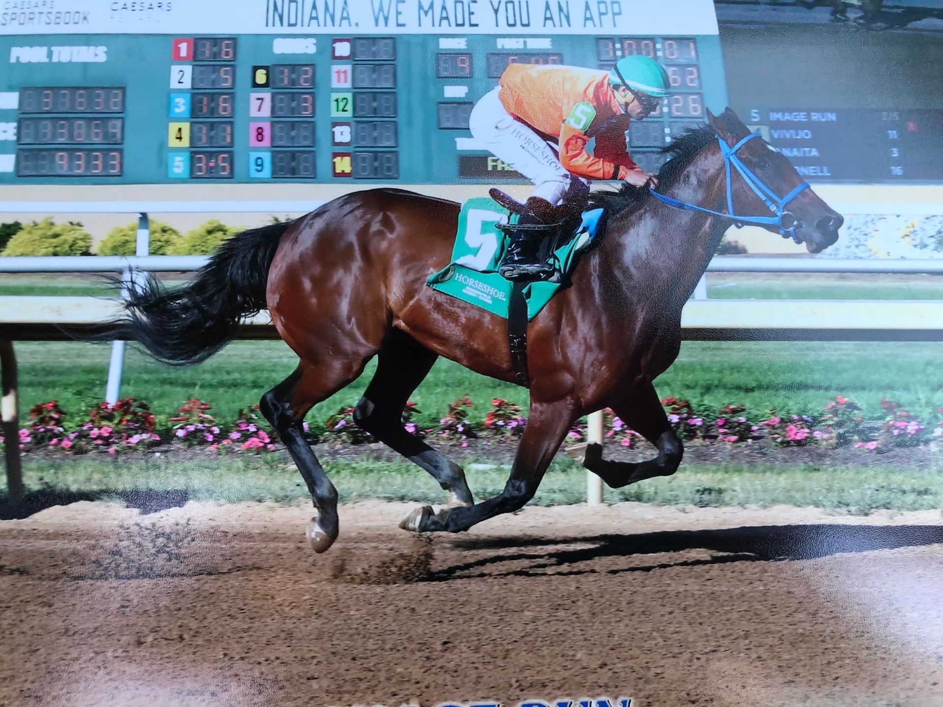 A jockey rides a horse in front of a scoreboard that says indiana we made you an app