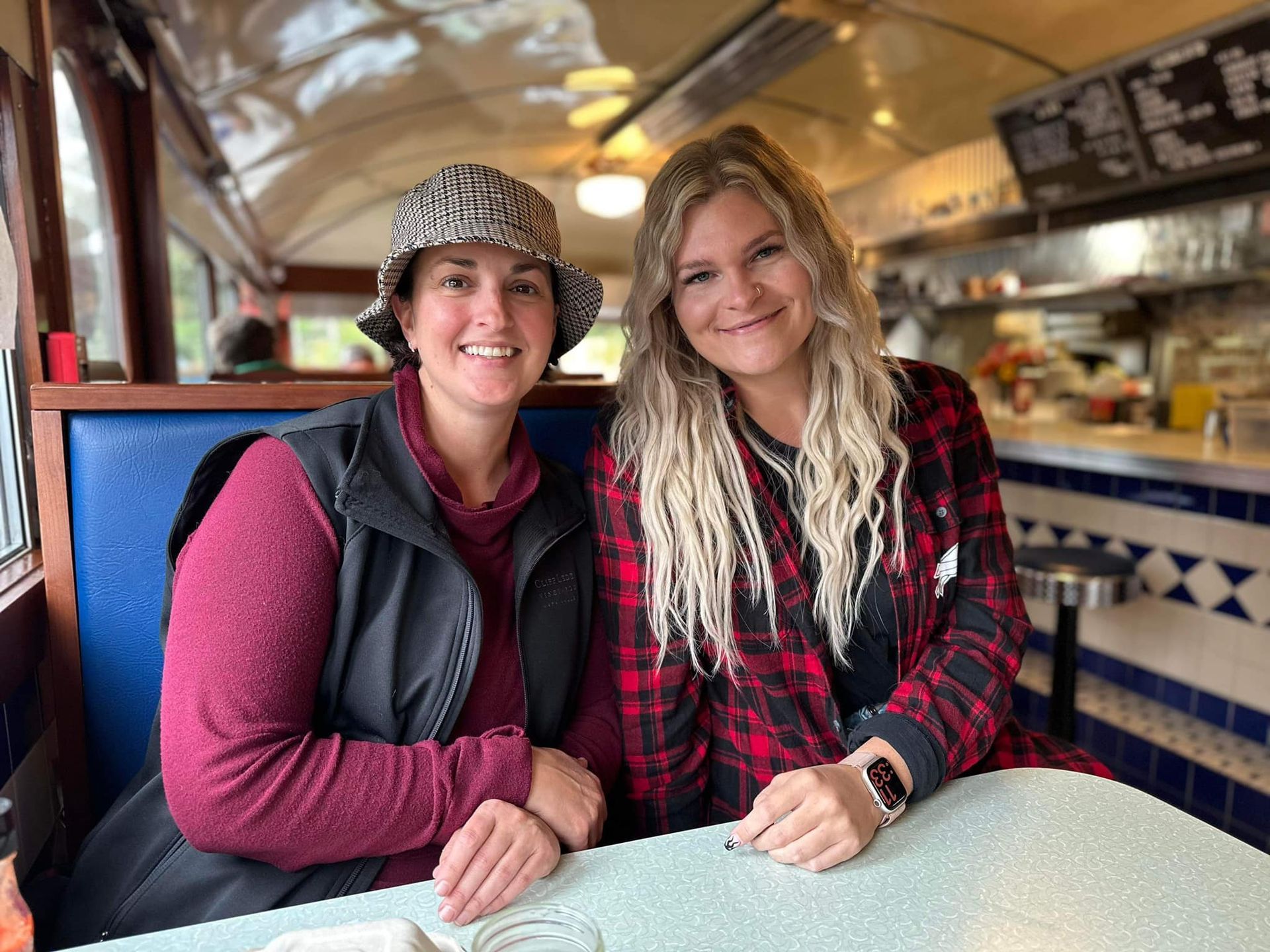Two women are sitting at a table in a diner.