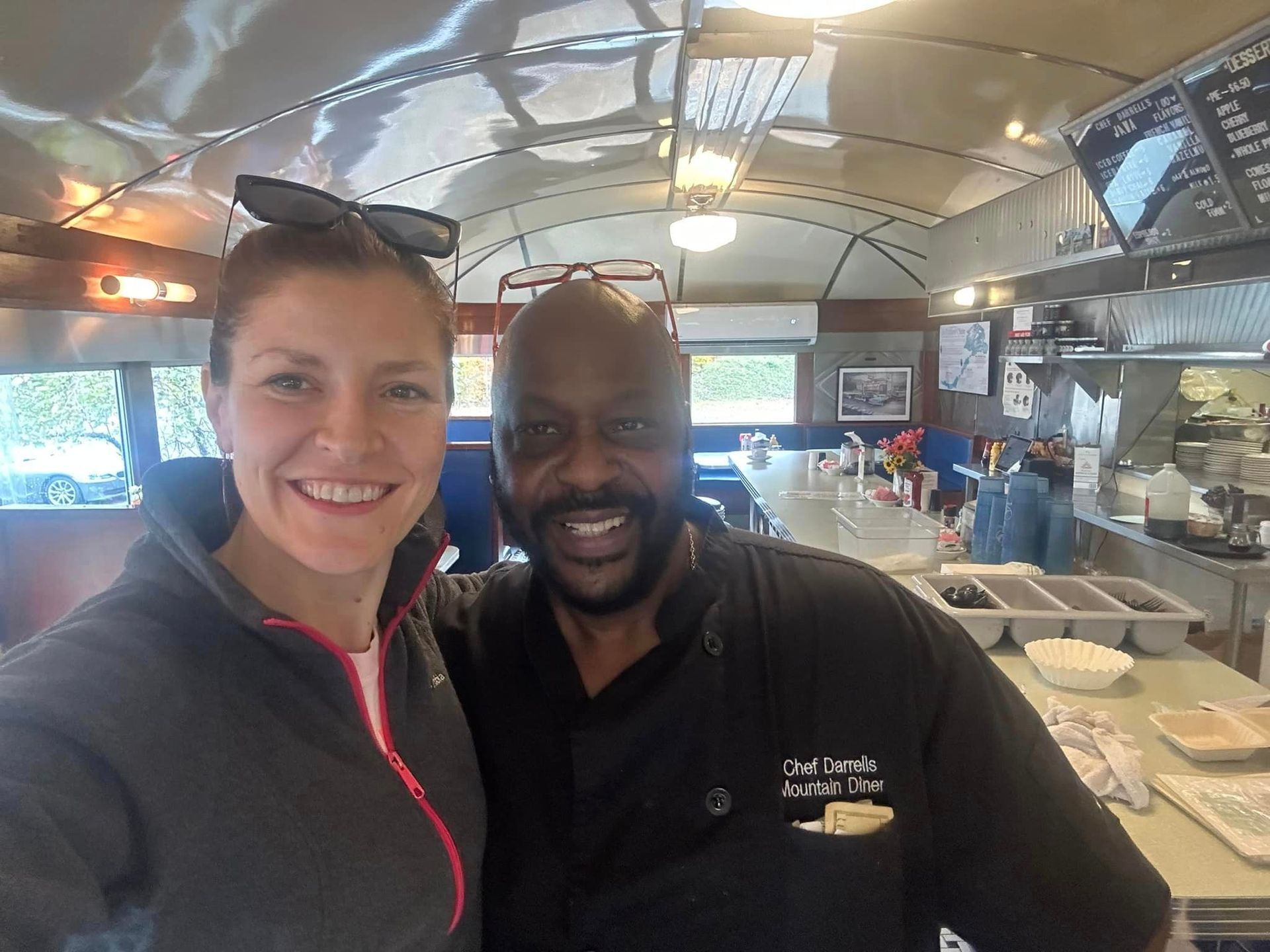 A man and a woman are posing for a picture in a restaurant kitchen.