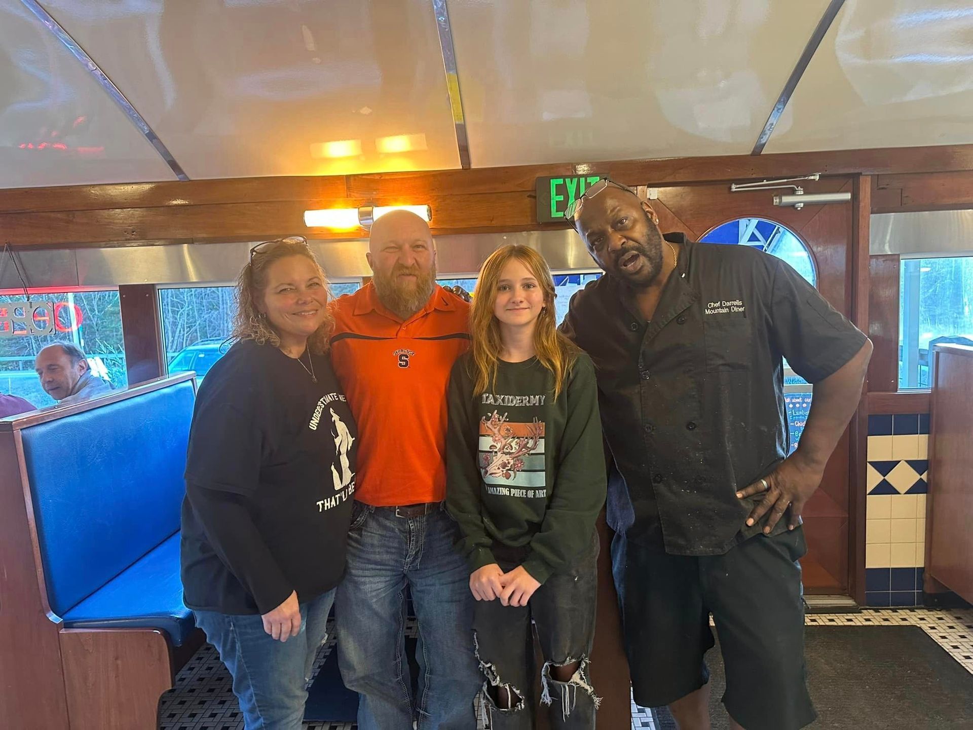 A group of people are posing for a picture in a diner.