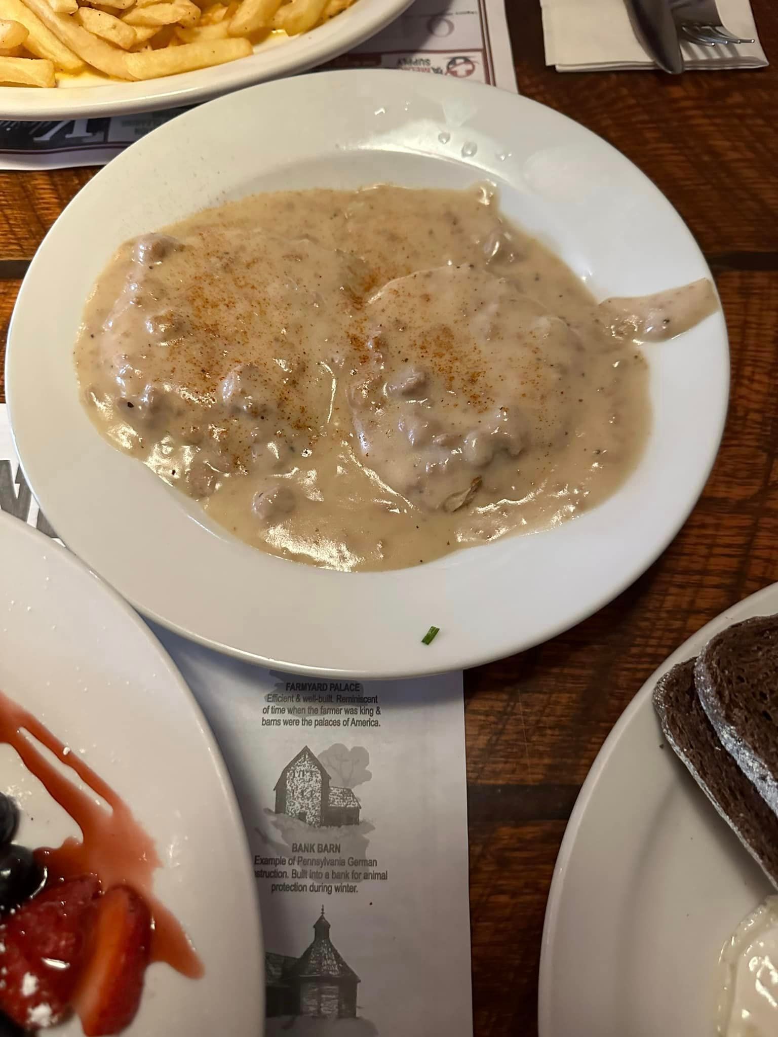 A plate of food with gravy and french fries on a table.