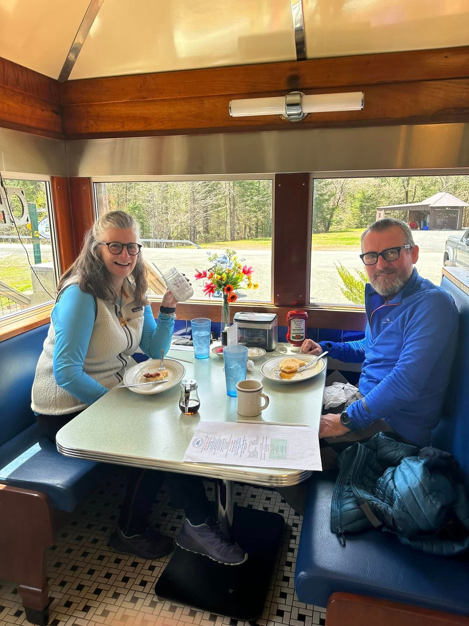 A man and a woman are sitting at a table in a diner.
