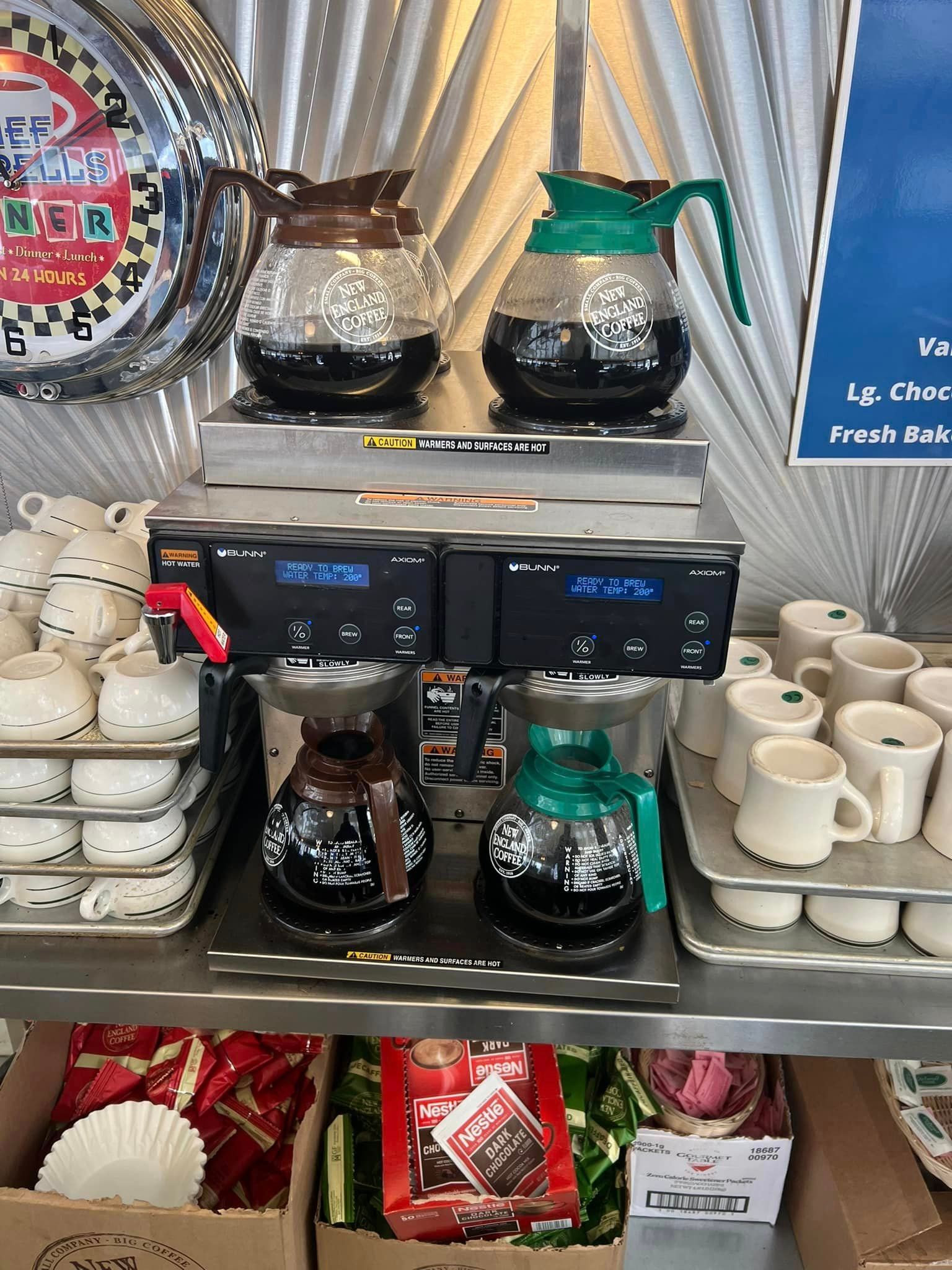 A coffee maker is sitting on top of a shelf next to a bunch of cups.