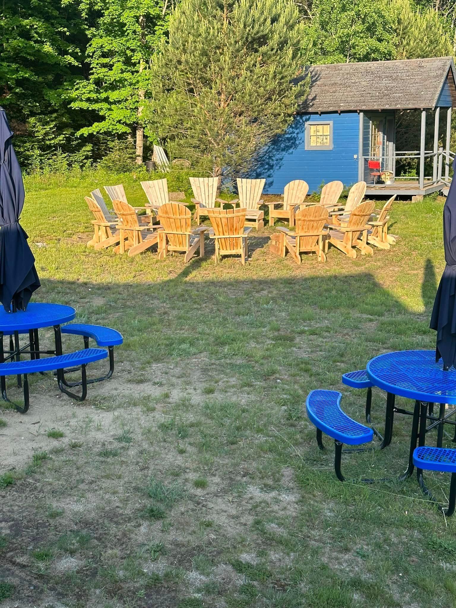 A group of blue picnic tables and chairs in a grassy field.