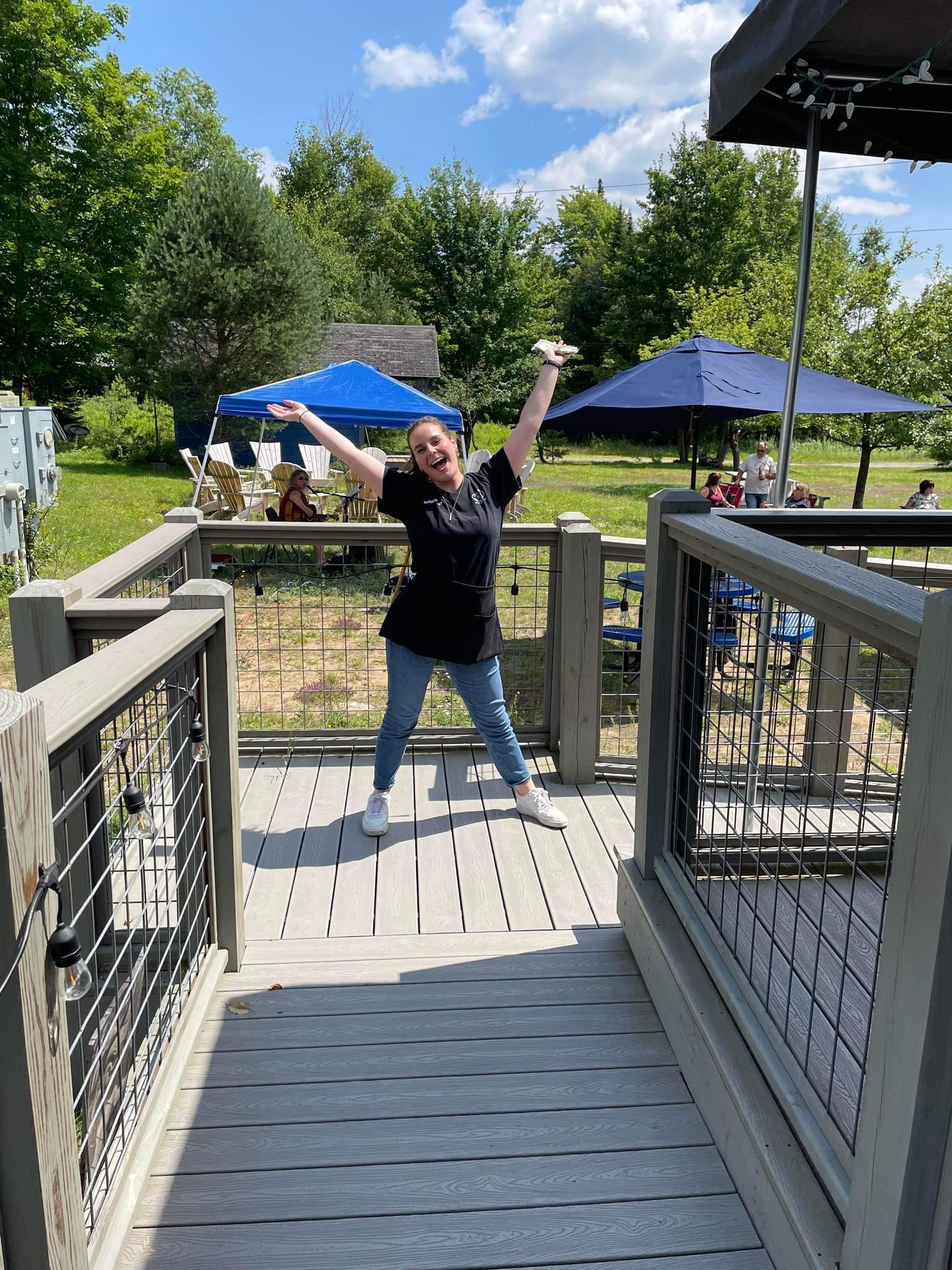 A woman is standing on a deck with her arms in the air.