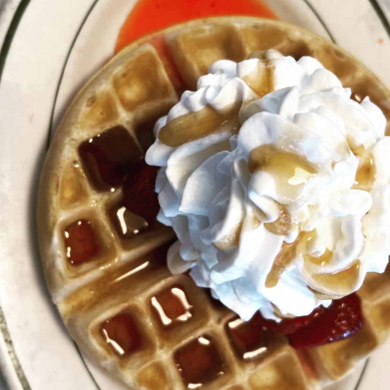 A waffle with whipped cream and syrup on top