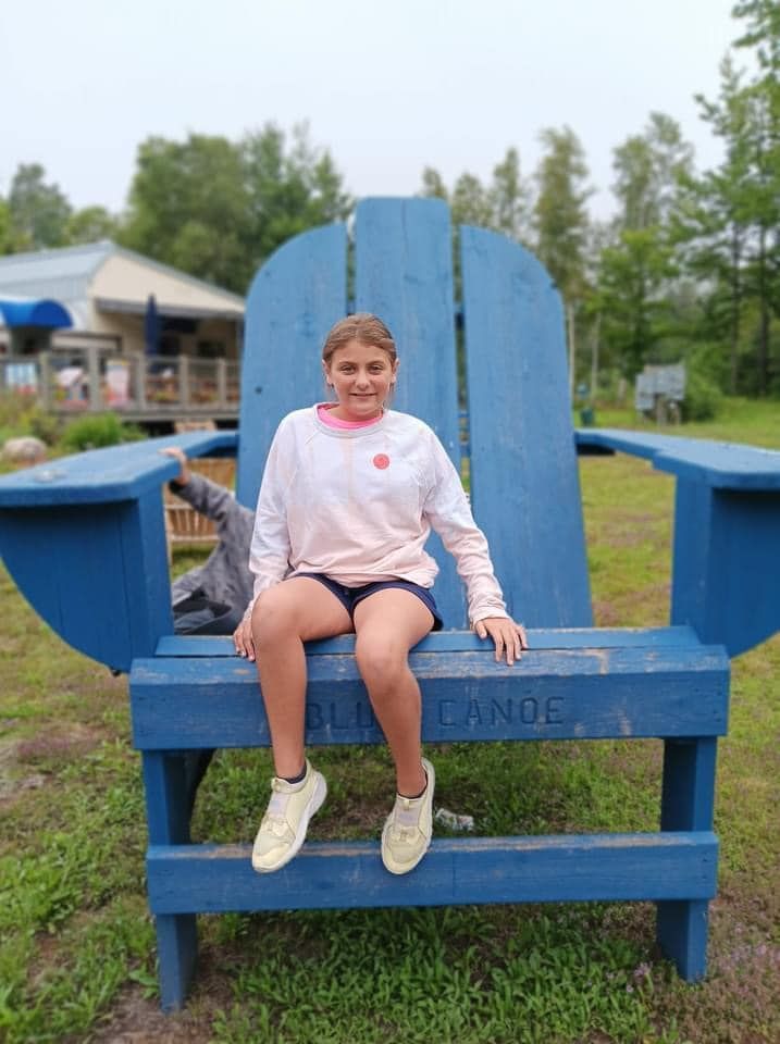 A young girl is sitting on a giant blue chair.