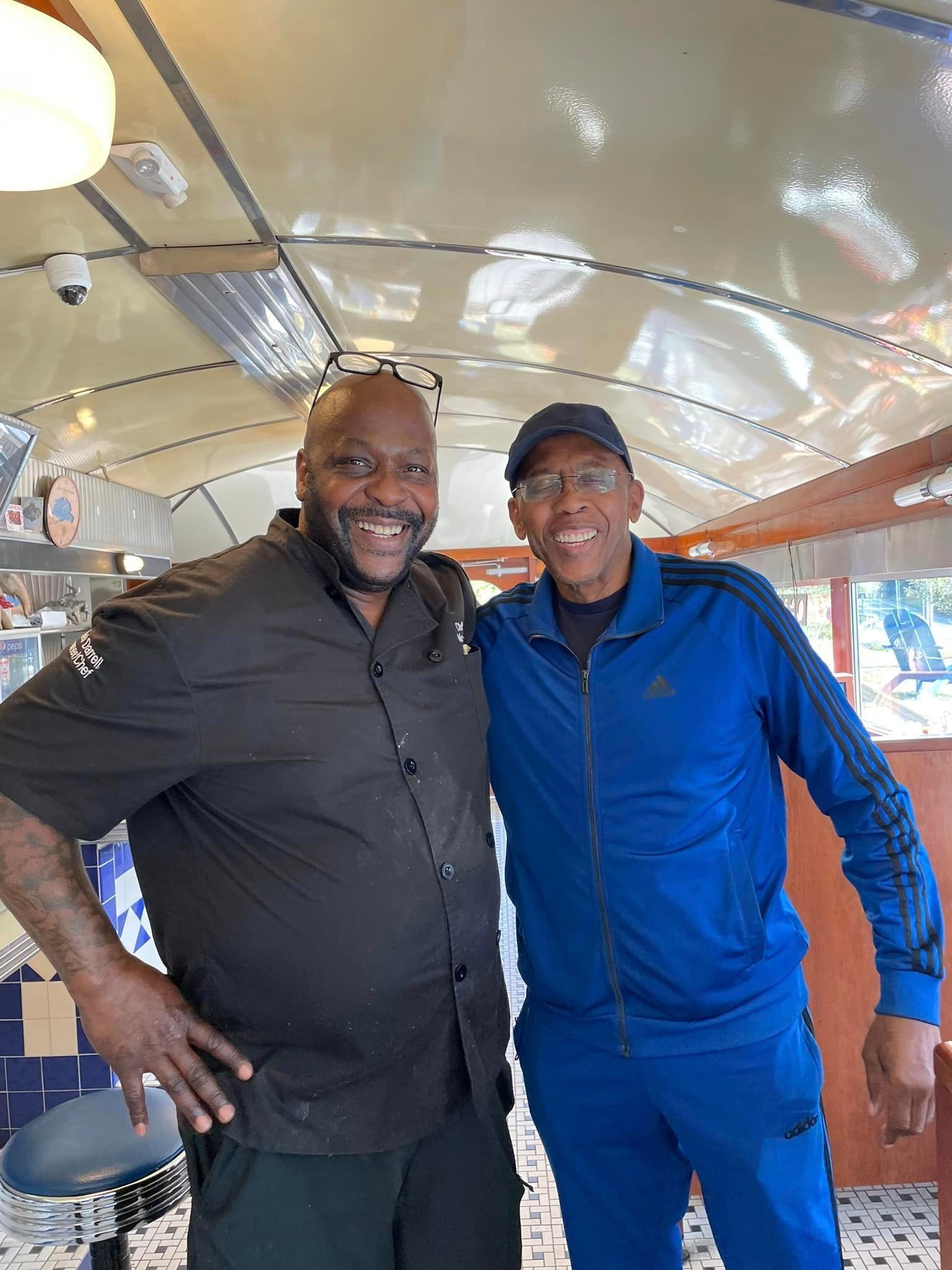 Two men are posing for a picture together in a diner.