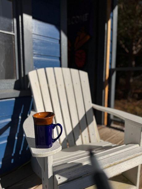 A white chair with a blue mug on the arm rest