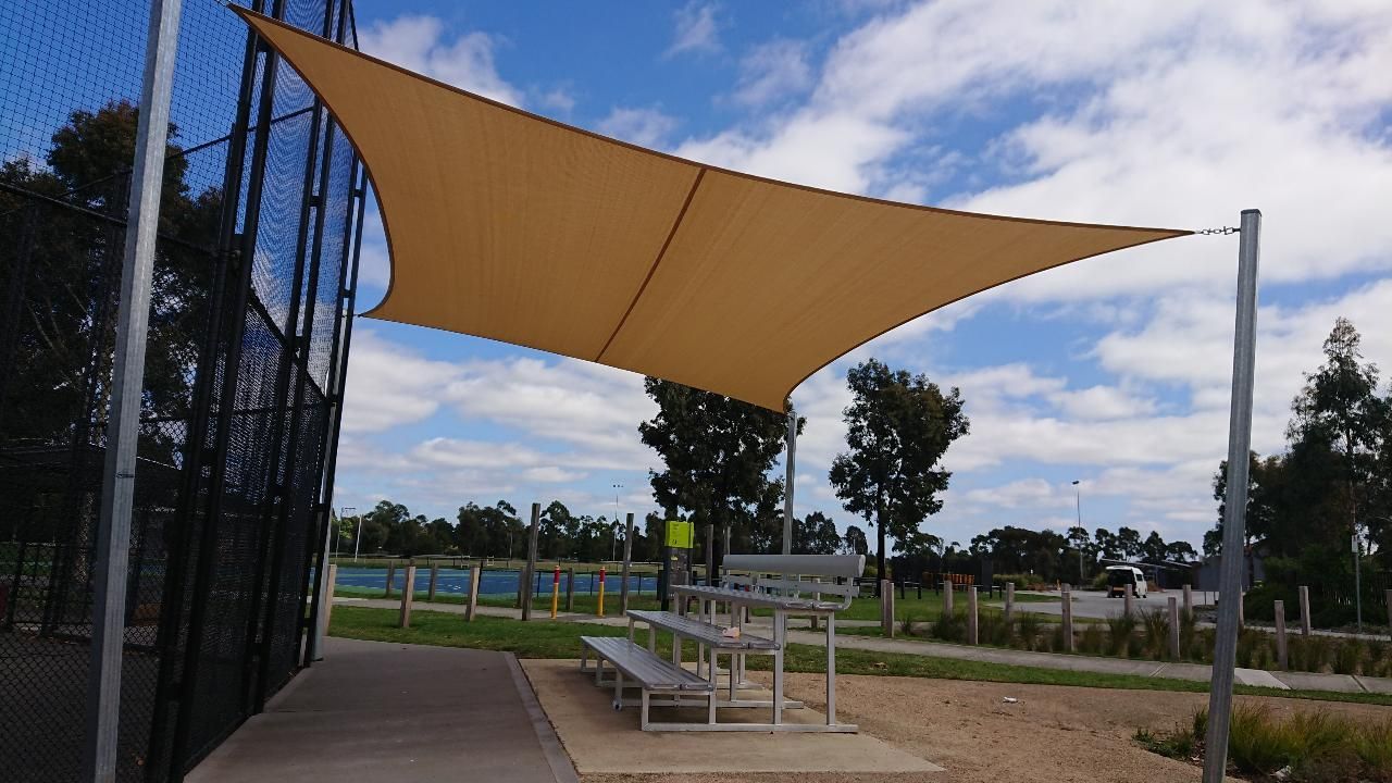 Large commercial-grade shade sail at Berwick Soft Ball Club covering spectator area in front of field over spectator area, offering all-weather protection and improving outdoor usability and aesthetics of the venue in a green recreational setting