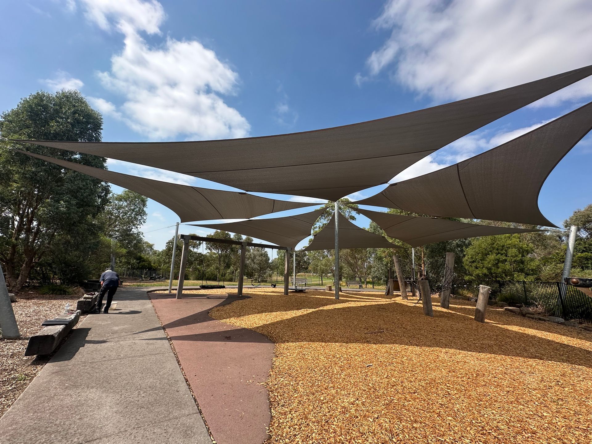 Commercial-grade custom shade sails installed over entire playground at Hampton Park Reserve for the City of Casey, providing full-coverage UV protection with tensioned fabric canopies supported by steel posts in a landscaped public space