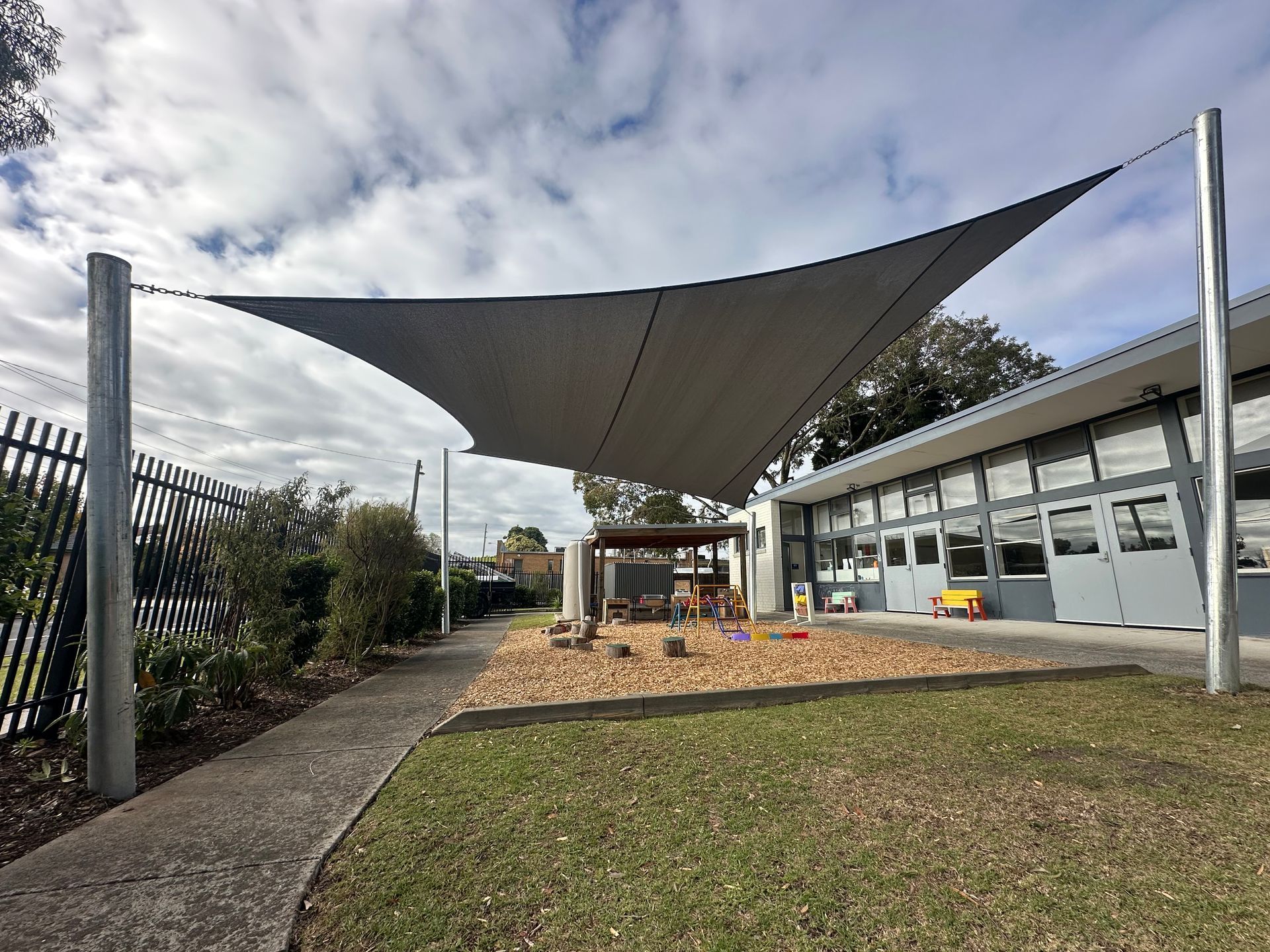 Shade sail installation over children’s play area at Casey Aboriginal Gathering Place in Doveton, featuring custom-designed UV-resistant fabric in earthy tones, providing sun protection and cultural gathering space functionality”