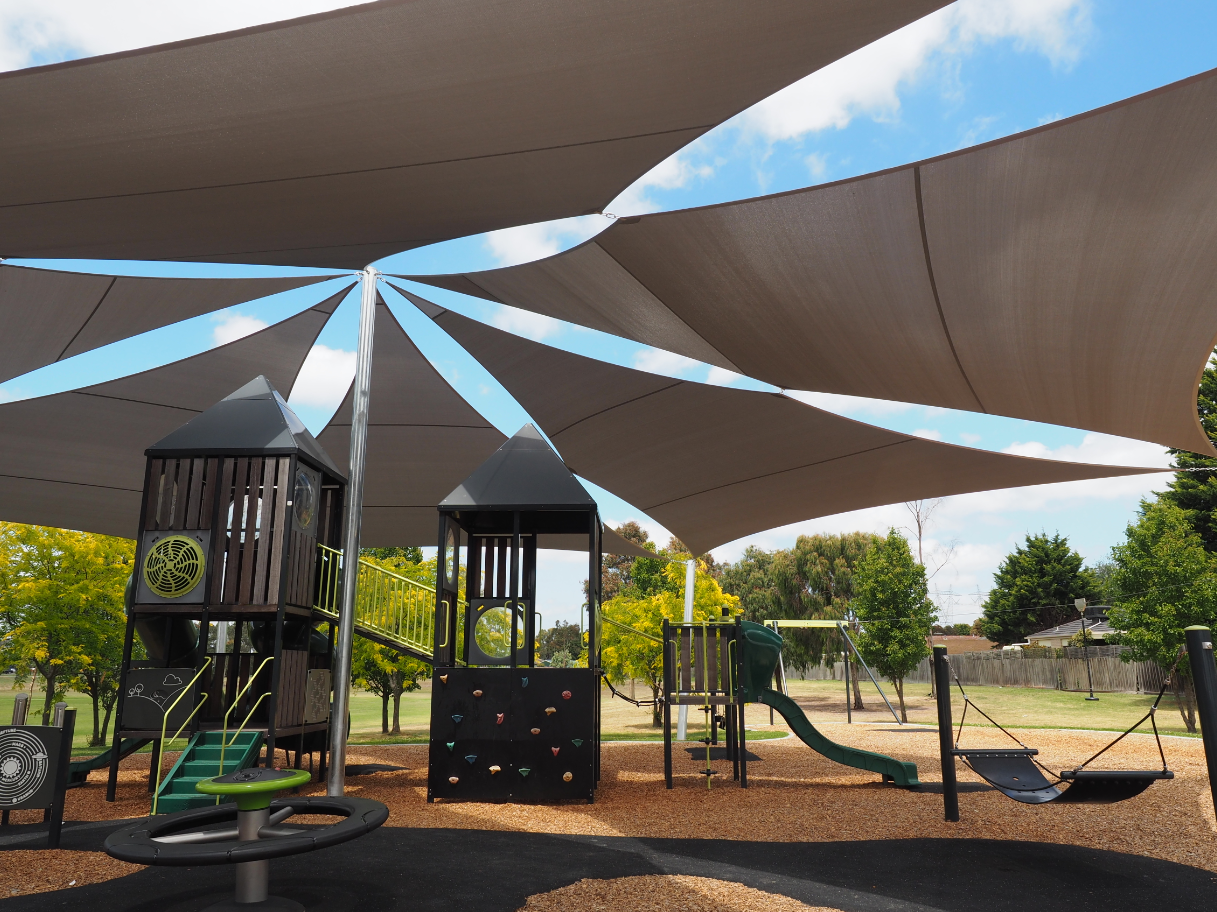 Custom shade sail system at Sambur Road Reserve in Tooradin, featuring multiple interconnected fabric canopies providing maximum sun protection for expansive children’s playground with natural surfacing and modern play equipment.
