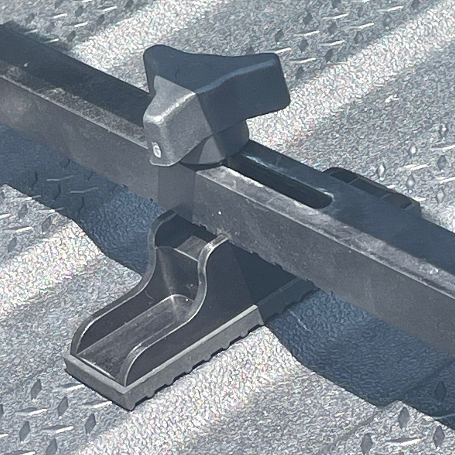 Black adjustable truck bed cargo bar with a tightening knob.