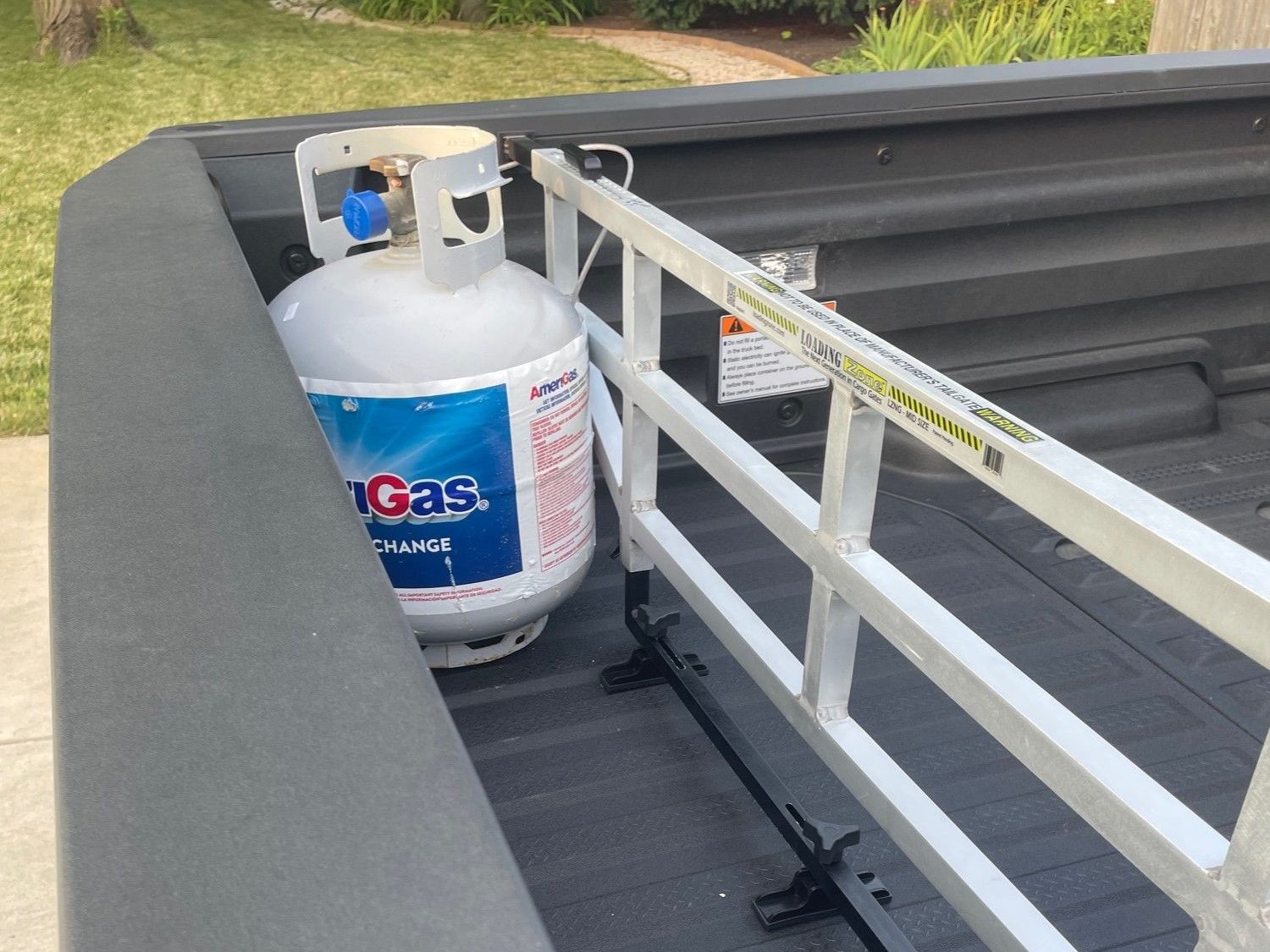 A propane tank secured in a truck bed by a bed divider.