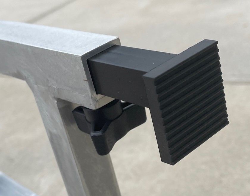 Close-up of a black rubber foot attached to a silver metal sawhorse leg, secured by a black knob.