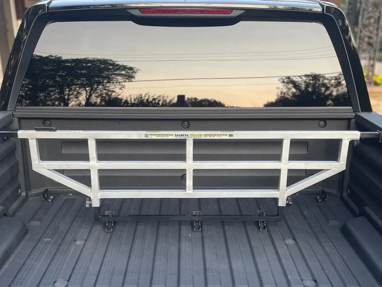 Silver metal truck bed cargo divider installed in a black truck bed.
