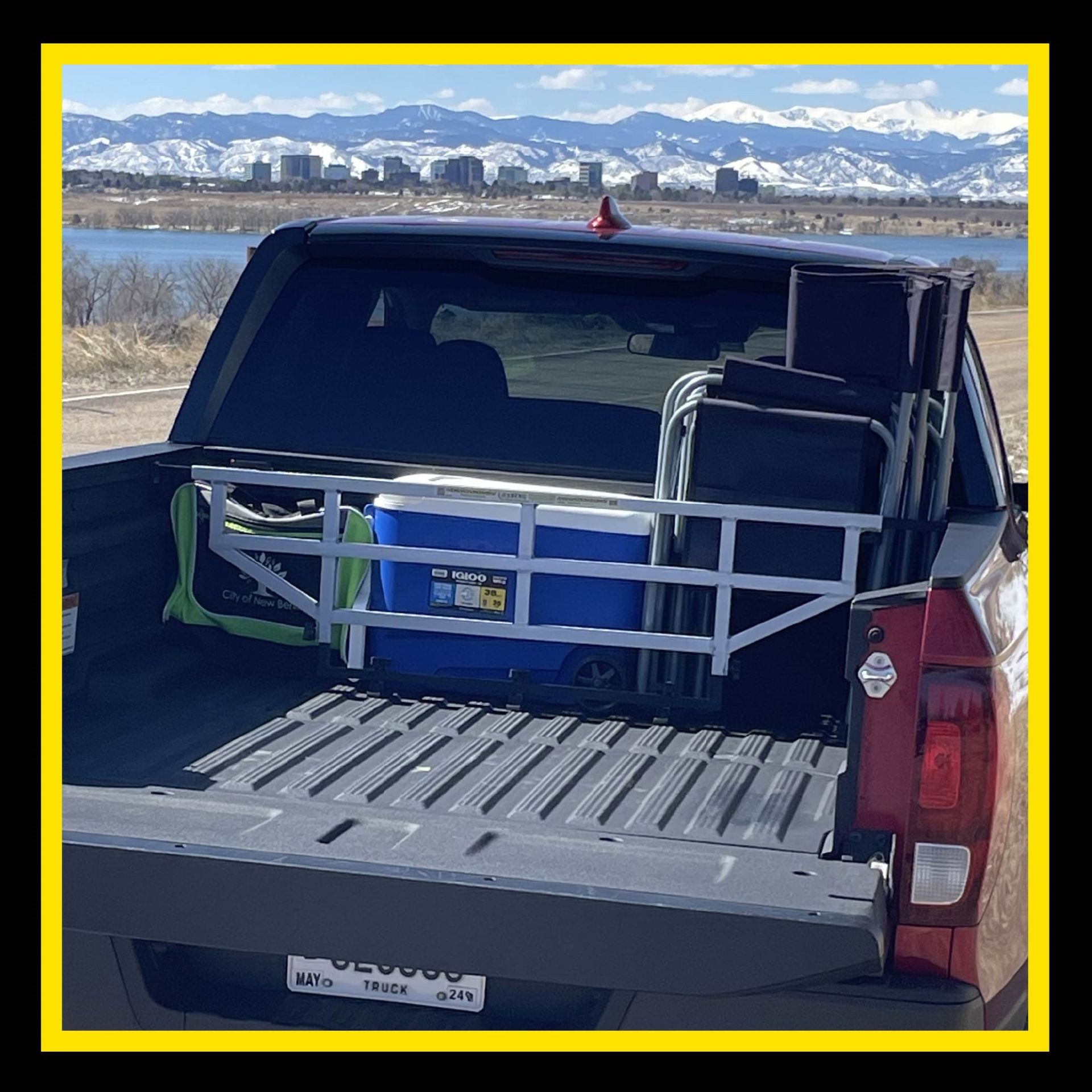 Truck bed loaded with cooler, chairs, and gear; mountains in background.