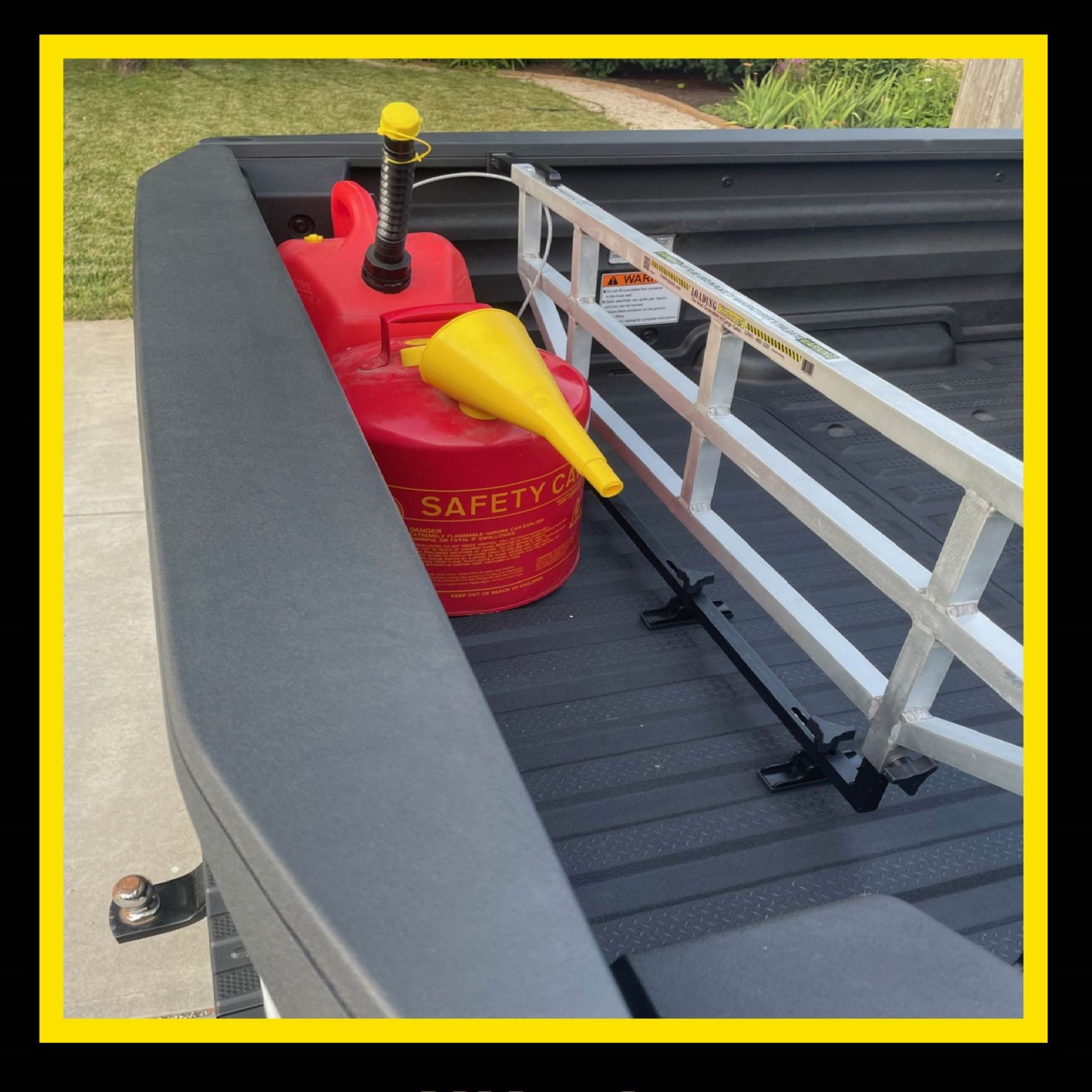 Red gas can and yellow funnel in the bed of a black truck. Aluminum rack secures them.