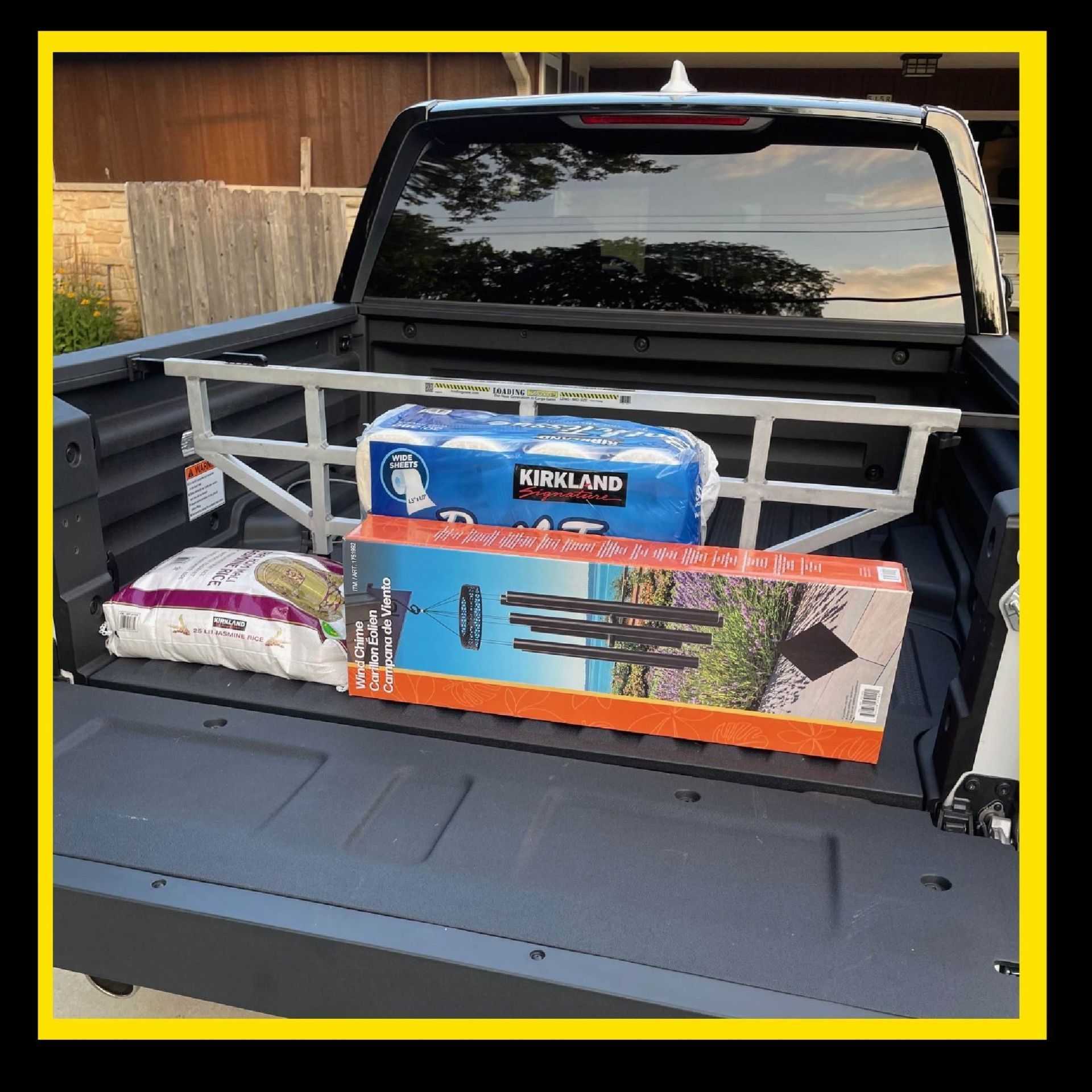 Truck bed with divider containing groceries and a long box.