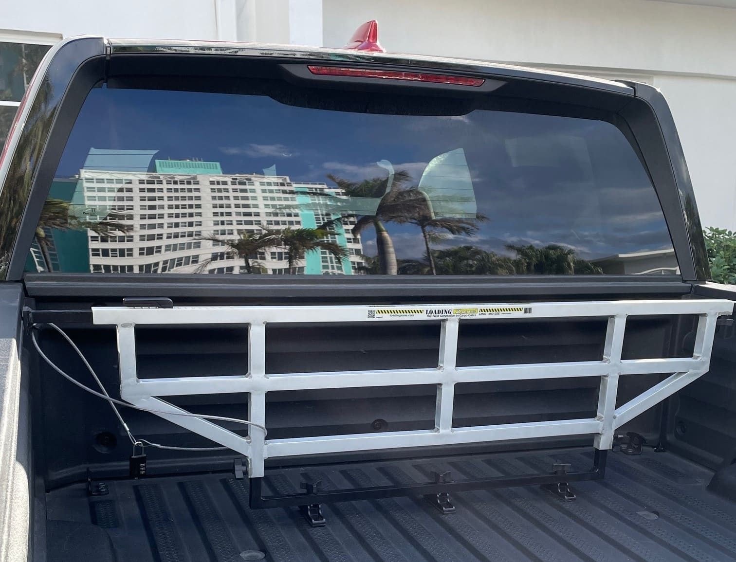 White truck bed rack installed against the rear window of a black truck.