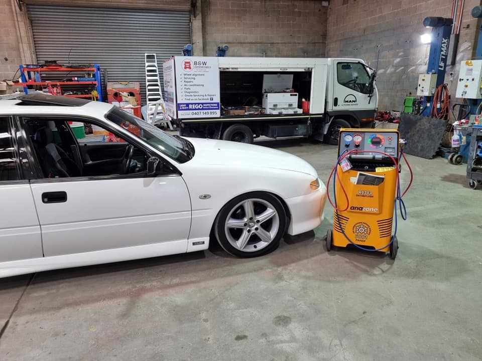 A White Car Is Parked In A Garage Next To A Truck — B & W Commercials In Wauchope, NSW