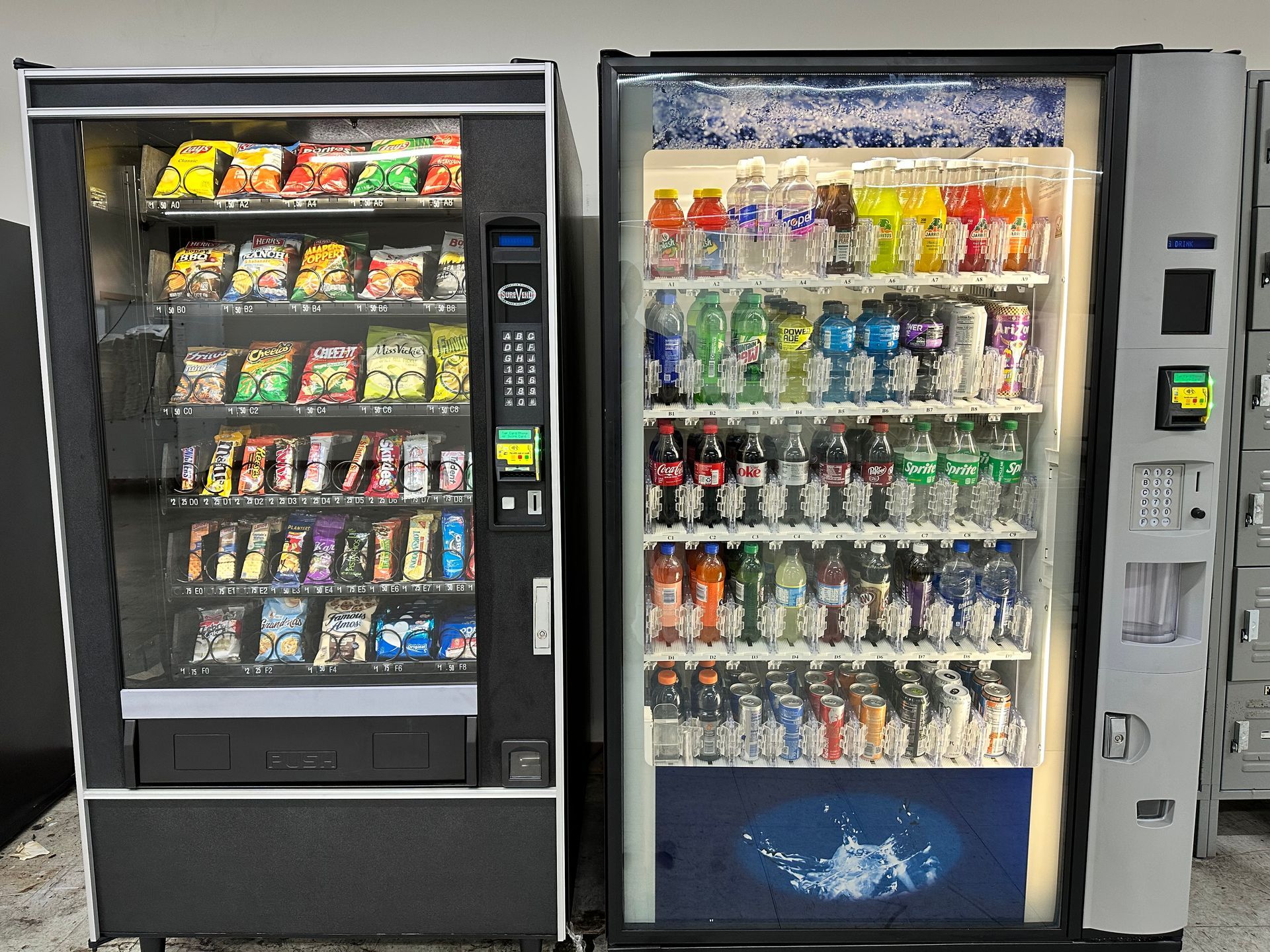 A person at a retail self-checkout kiosk using a smartphone to pay for snacks and a beverage.