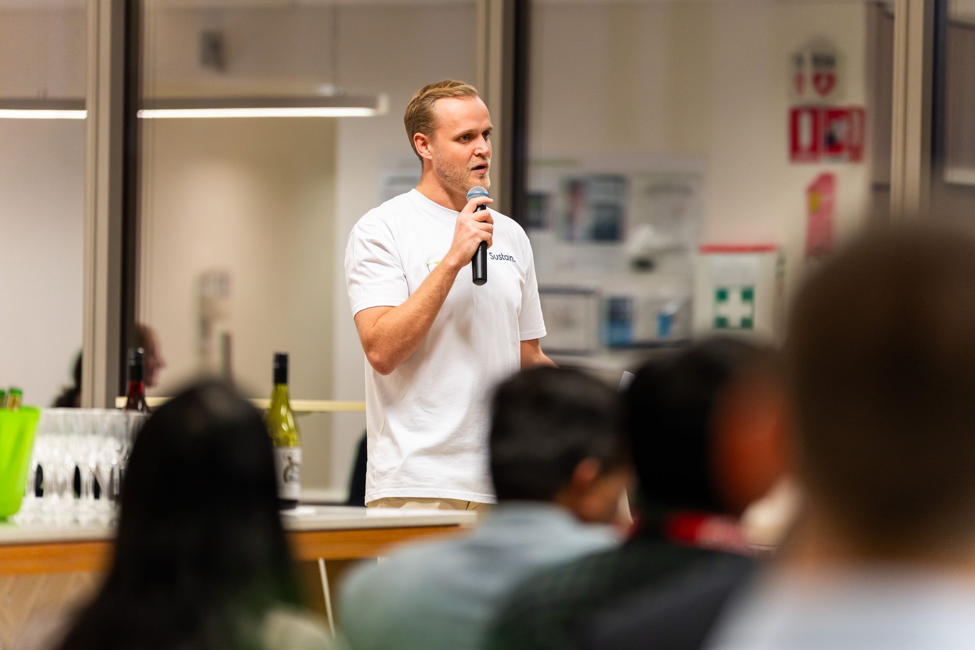 A man is speaking into a microphone in front of a group of people.
